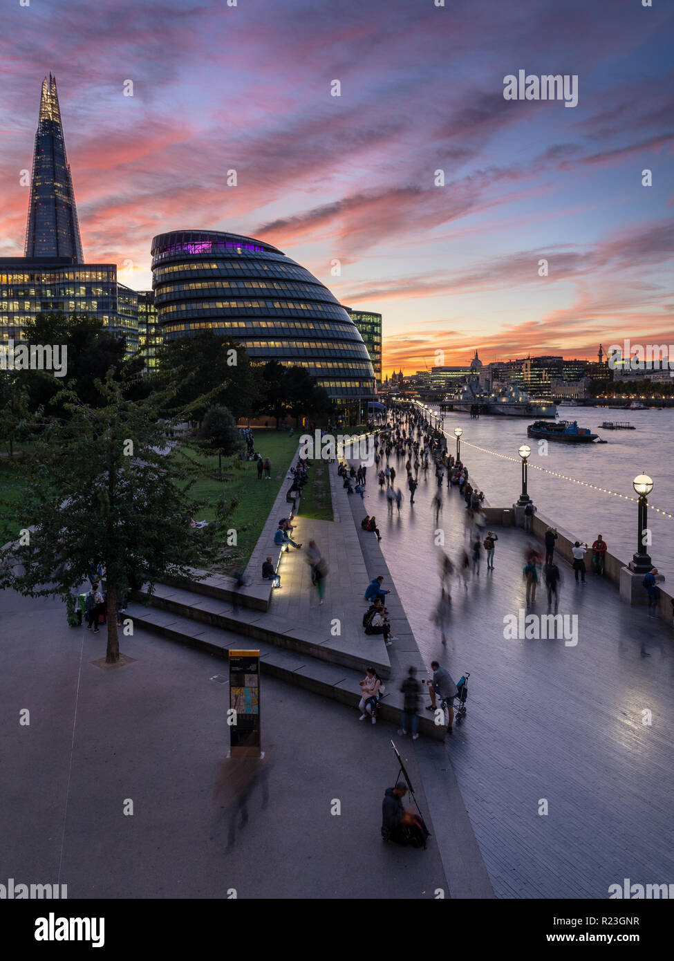 London, England, Regno Unito - 27 Settembre 2018: i turisti a piedi lungo il Tamigi percorso e prendere le fotografie dei punti di riferimento di Londra come il sole tramonta dietro alla City Hal Foto Stock