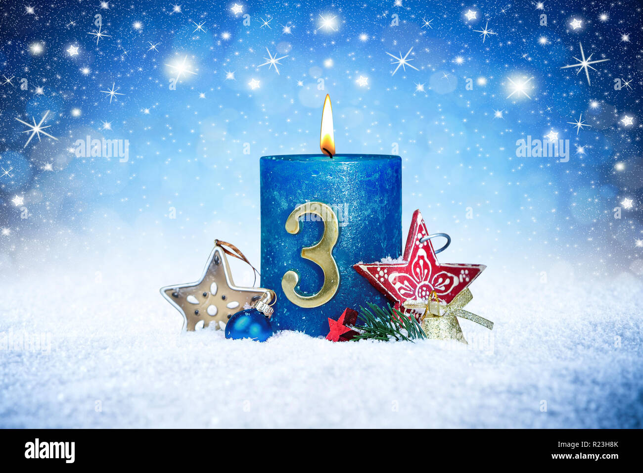 Terza domenica di Avvento la candela blu con metallo dorato rosso numero uno di decorazione su assi di legno in snow anteriore del panorama di argento sfondo bokeh di fondo Foto Stock