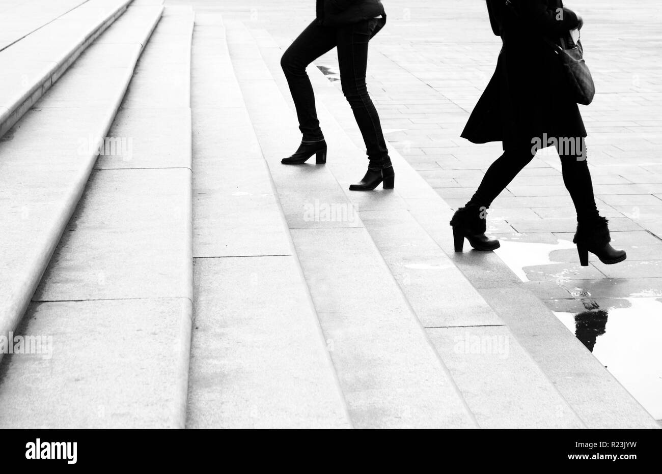 Due giovani donne a camminare su e giù per la città enorme scale muovendo al di là di ogni altra, in bianco e nero Foto Stock