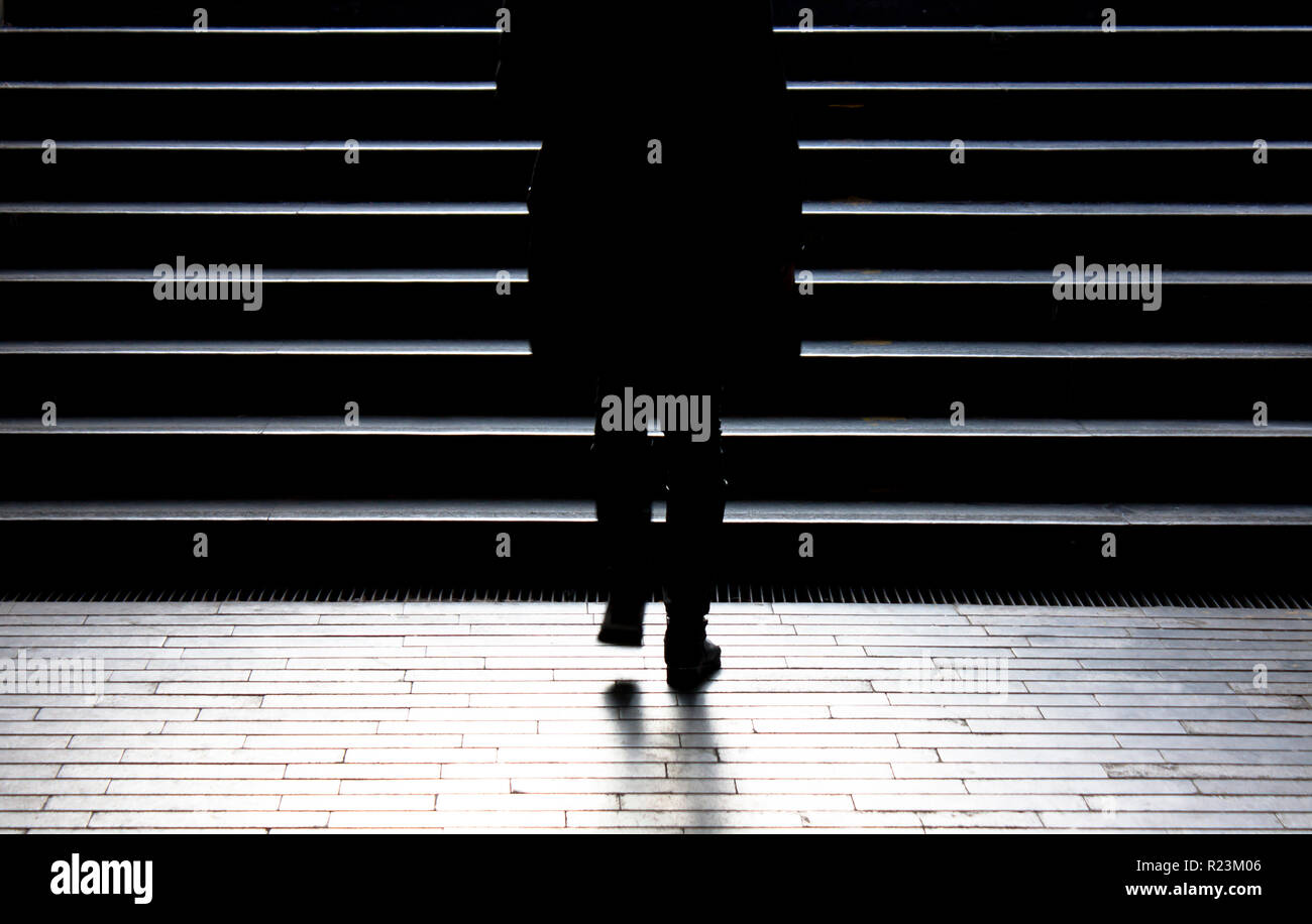 Urbano a piedi di notte : sfocata silhouette di donna giovane salendo per la strada di città scale pubbliche nel tranquillo inverno moonlight , da sola, da dietro Foto Stock