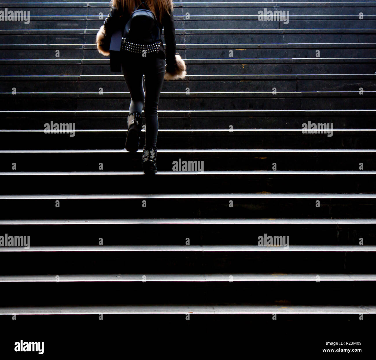 Sfocata giovane donna in costume grunge salendo per la strada di città scale pubbliche, da dietro Foto Stock
