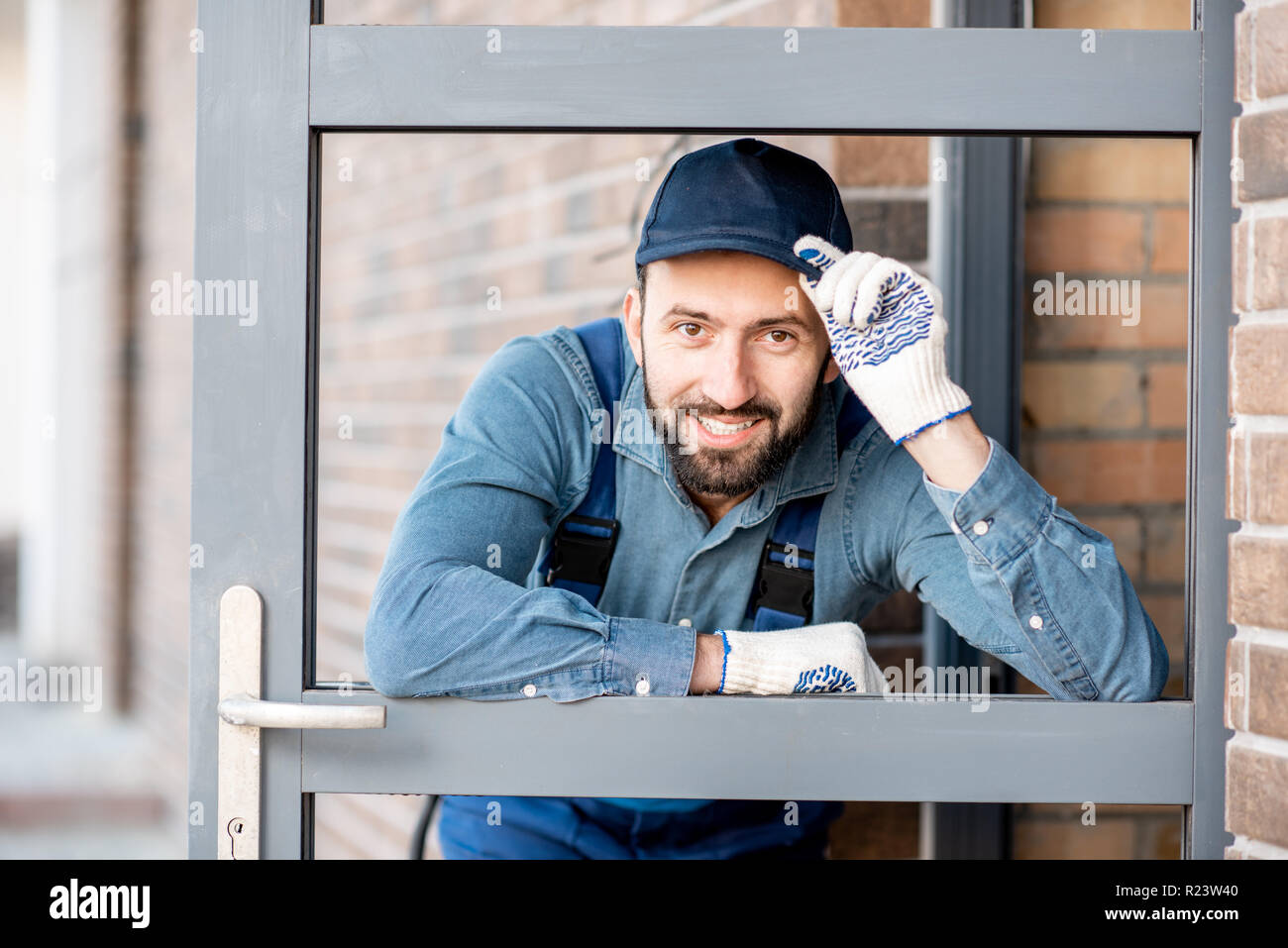 Divertente ritratto di un builder guardando attraverso la porta di ingresso di una nuova casa all'aperto Foto Stock
