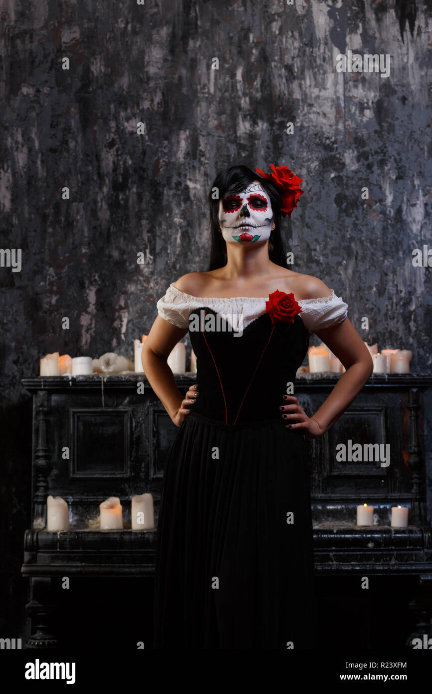 Ritratto di donna di zombie con faccia bianca e fiore rosso sul suo capo Foto Stock