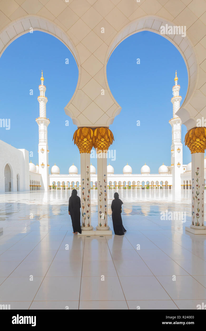 2 (due) donne turistica indossando il tradizionale nero abbigliamento Abaya ammirando la bellezza della Sheikh Zayed Grande Moschea di Abu Dhabi, negli Emirati Arabi Uniti. Foto Stock