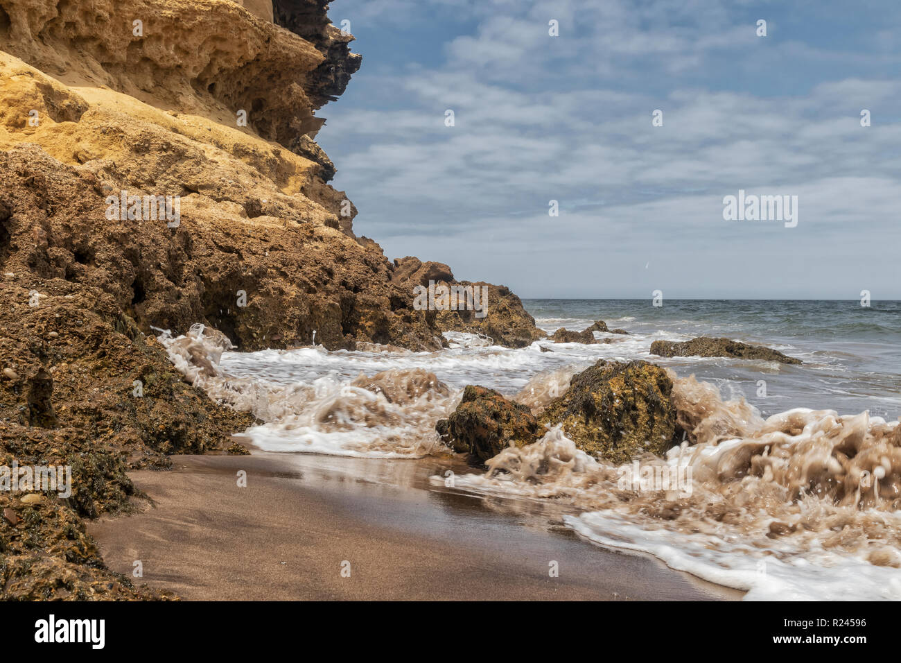 Canyon su Namibe spiaggia deserta. Spiaggia selvaggia con rocce e spruzzi di acqua di mare. L'Africa. Angola. Namibe. Foto Stock