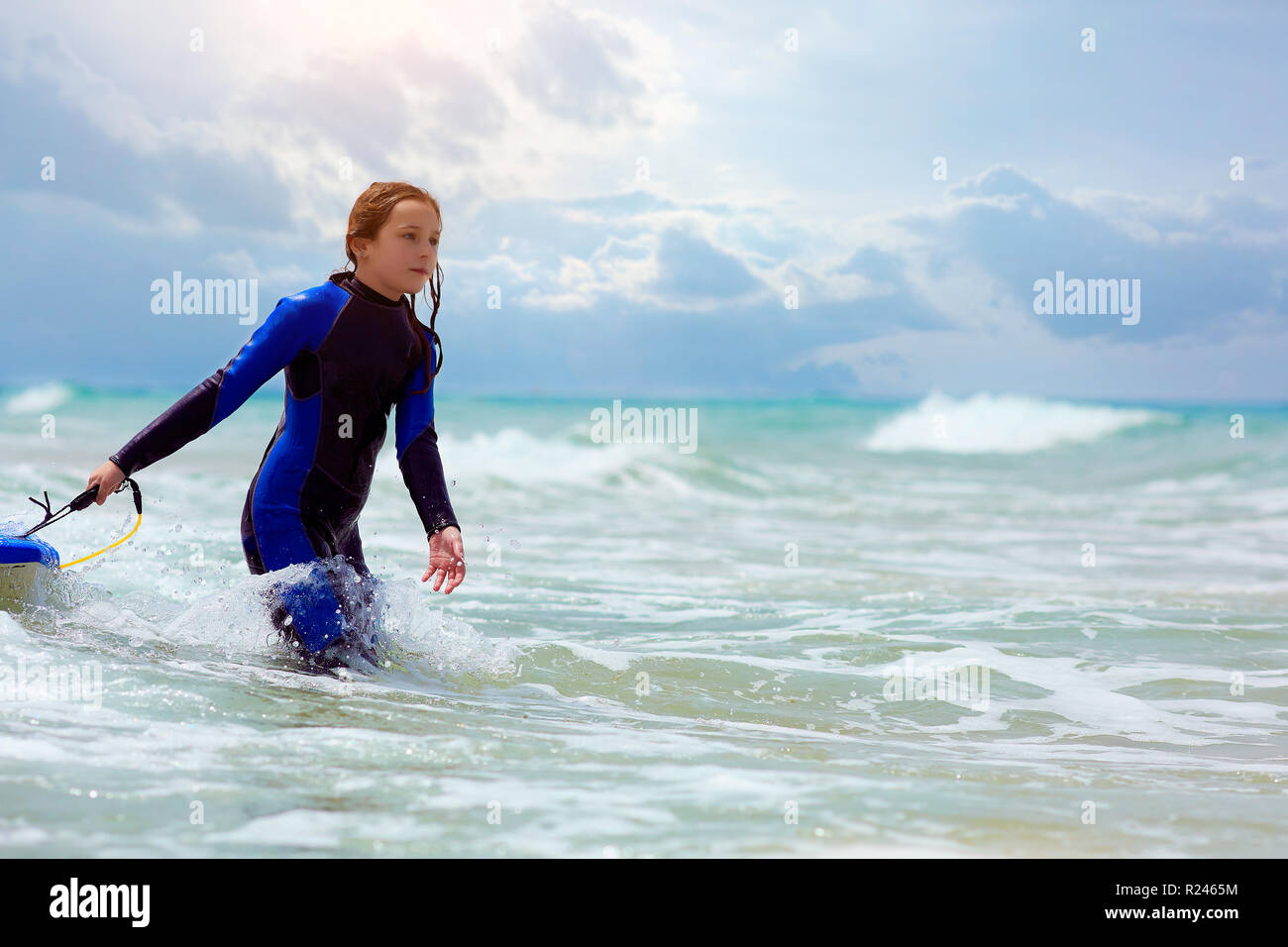 La ragazza con la tavola da surf passeggiate in mare Foto Stock