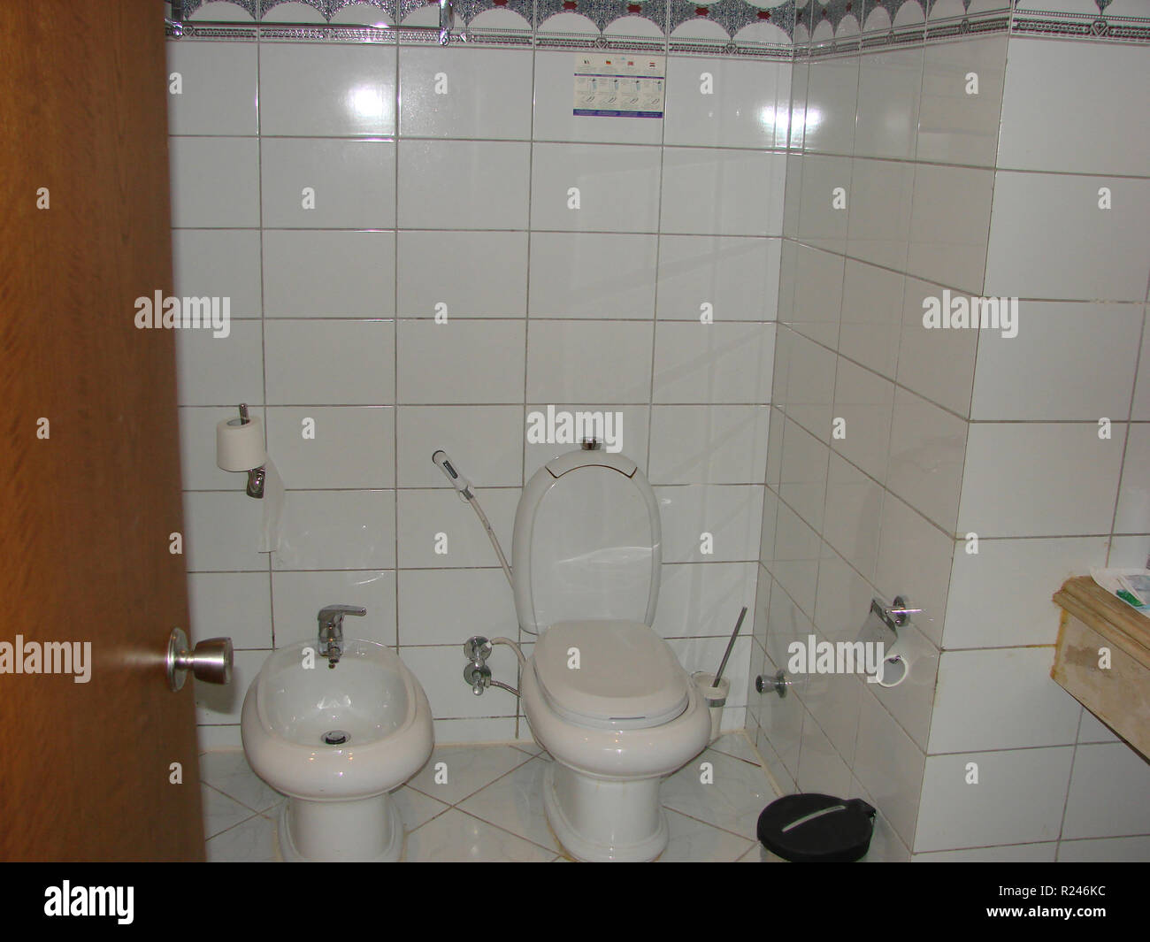 La ceramica bianca wc e bidet si trova su un pavimento bianco piastrella Foto Stock