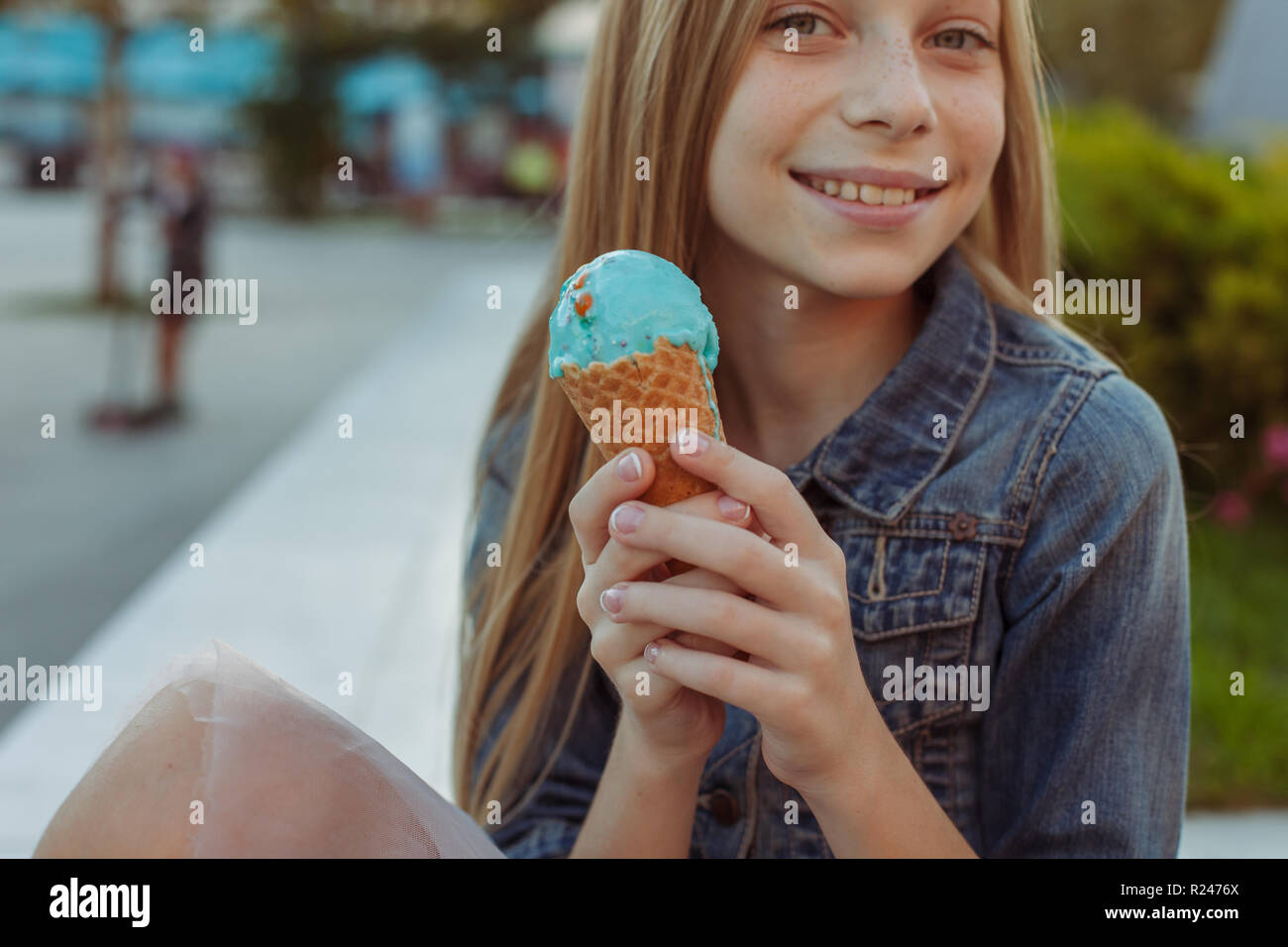 Carino e felice giovane ragazza a mangiare il gelato al di fuori Foto Stock