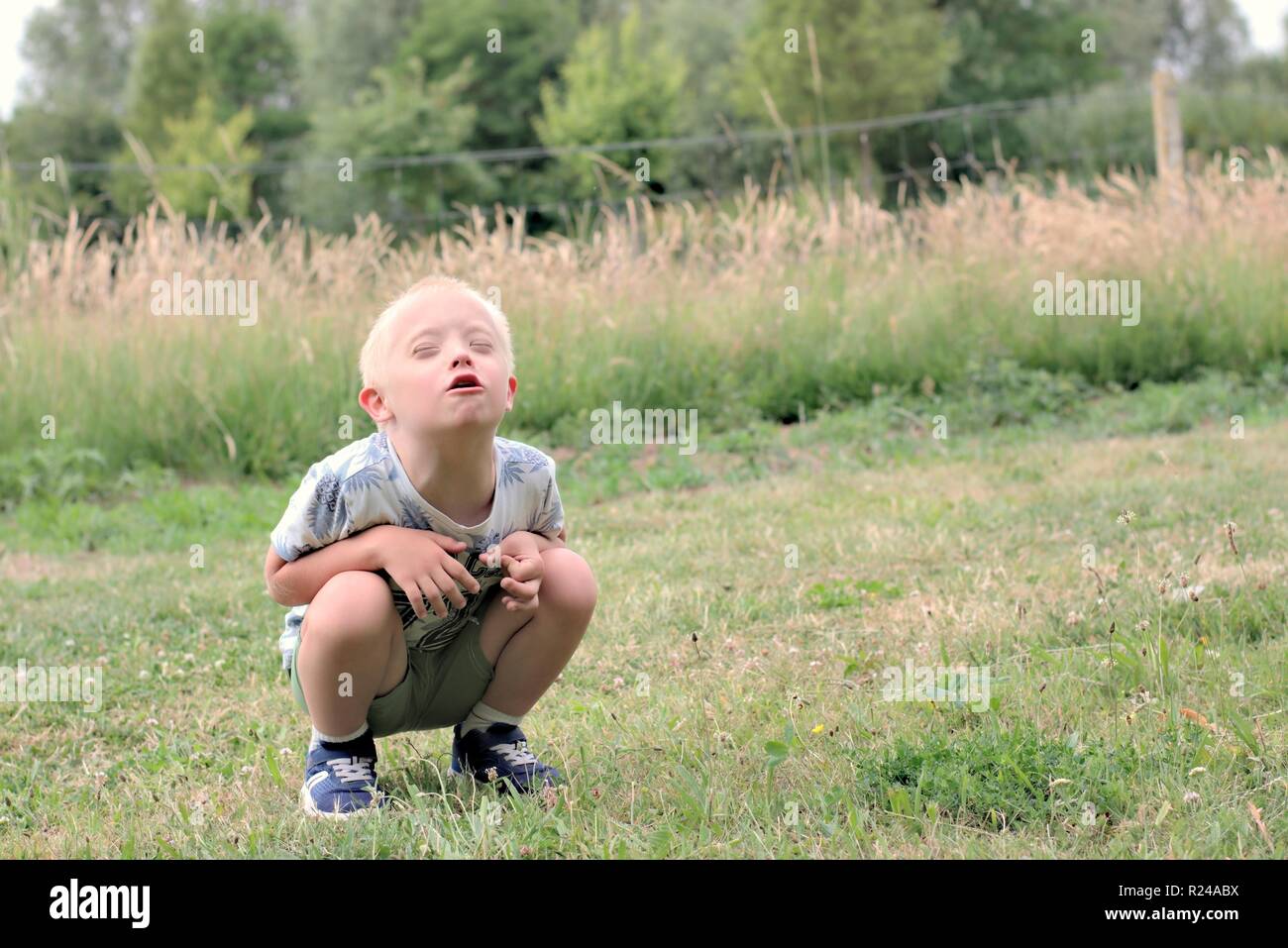 Difetto,l'infanzia,medicina e persone concetto- ragazzo con la sindrome di down comporta per un ritratto all'esterno. Foto Stock