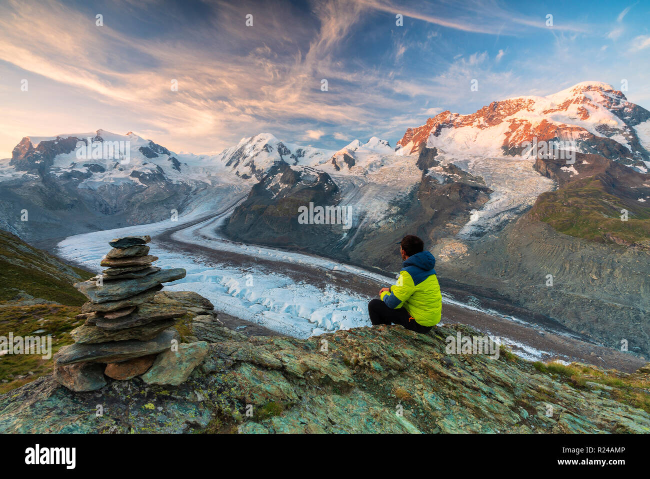 Escursionista seduti sulle rocce guardando verso il Monte Rosa ghiacciaio Zermatt, canton Vallese, alpi svizzere, Svizzera, Europa Foto Stock