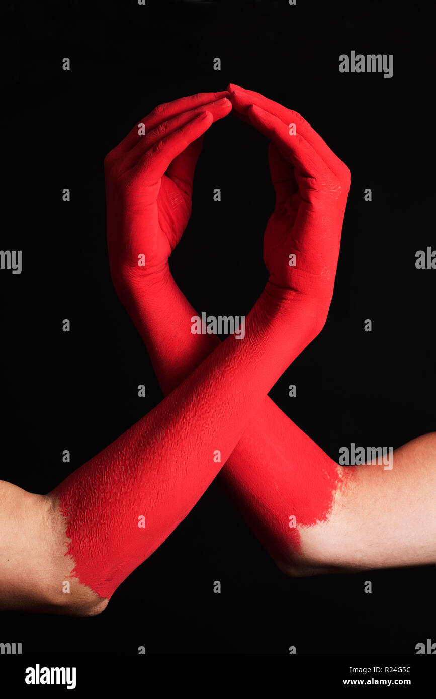Primo piano dei bracci di due uomini dipinte di rosso formando un rosso nastro di sensibilizzazione per la lotta contro l AIDS, contro uno sfondo nero Foto Stock