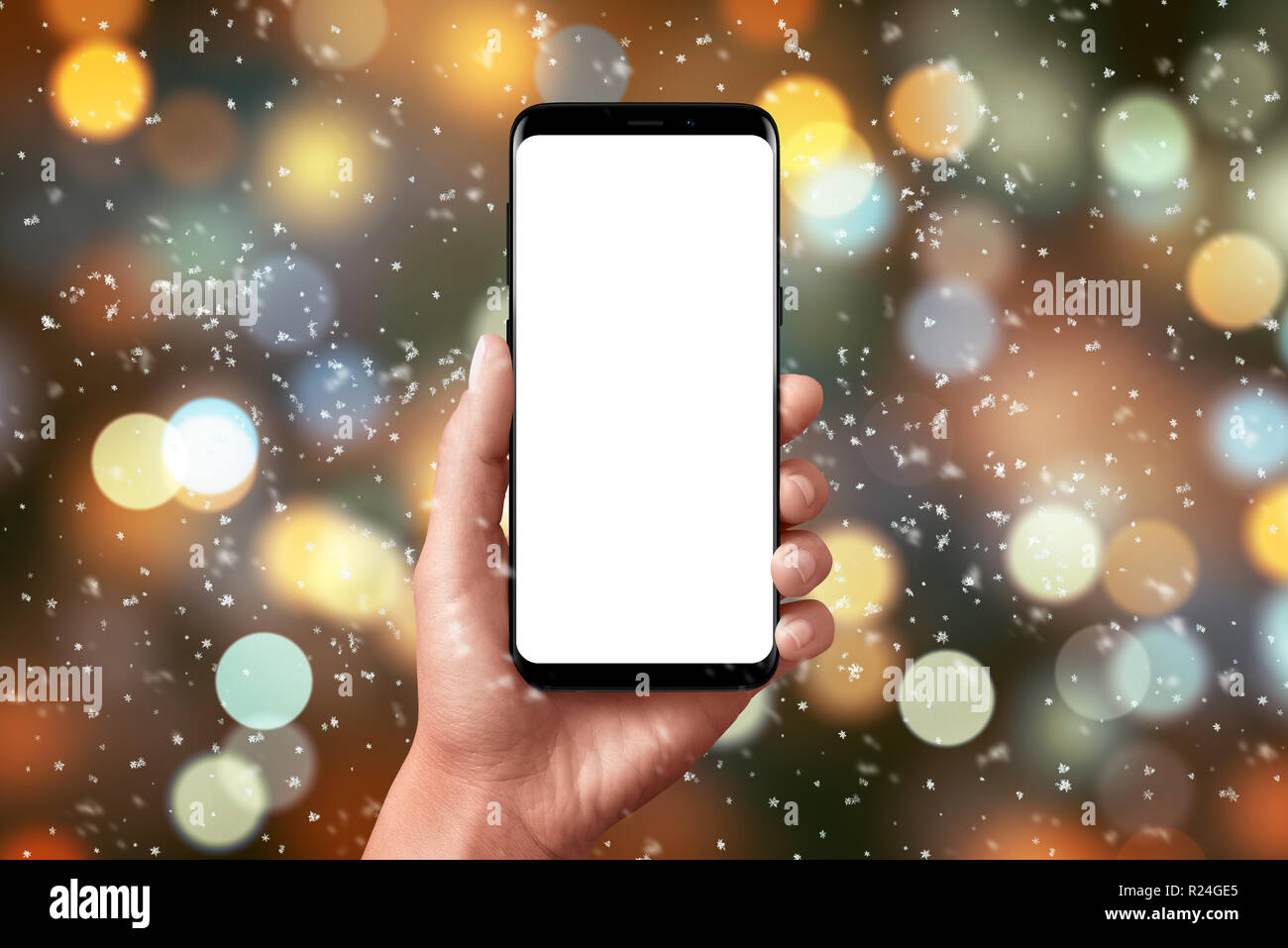 Le luci di Natale e bokeh di fondo. Smart phone in mano con schermo isolato per mockup, app o un sito web design presentazione. Foto Stock