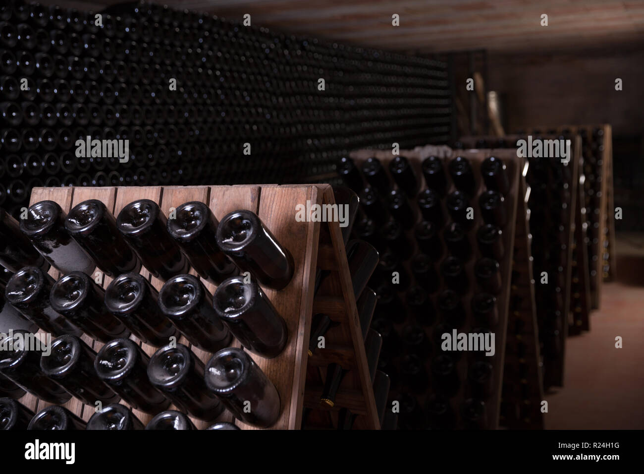 Invecchiamento del vino in bottiglia su scaffalature in legno in cantina  Foto stock - Alamy