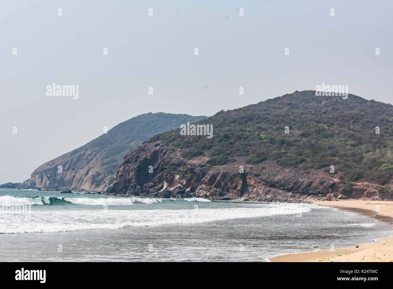 Una bella spiaggia di mare con una vista rocciosa delle montagne che guarda impressionante in giornata di sole. Foto Stock