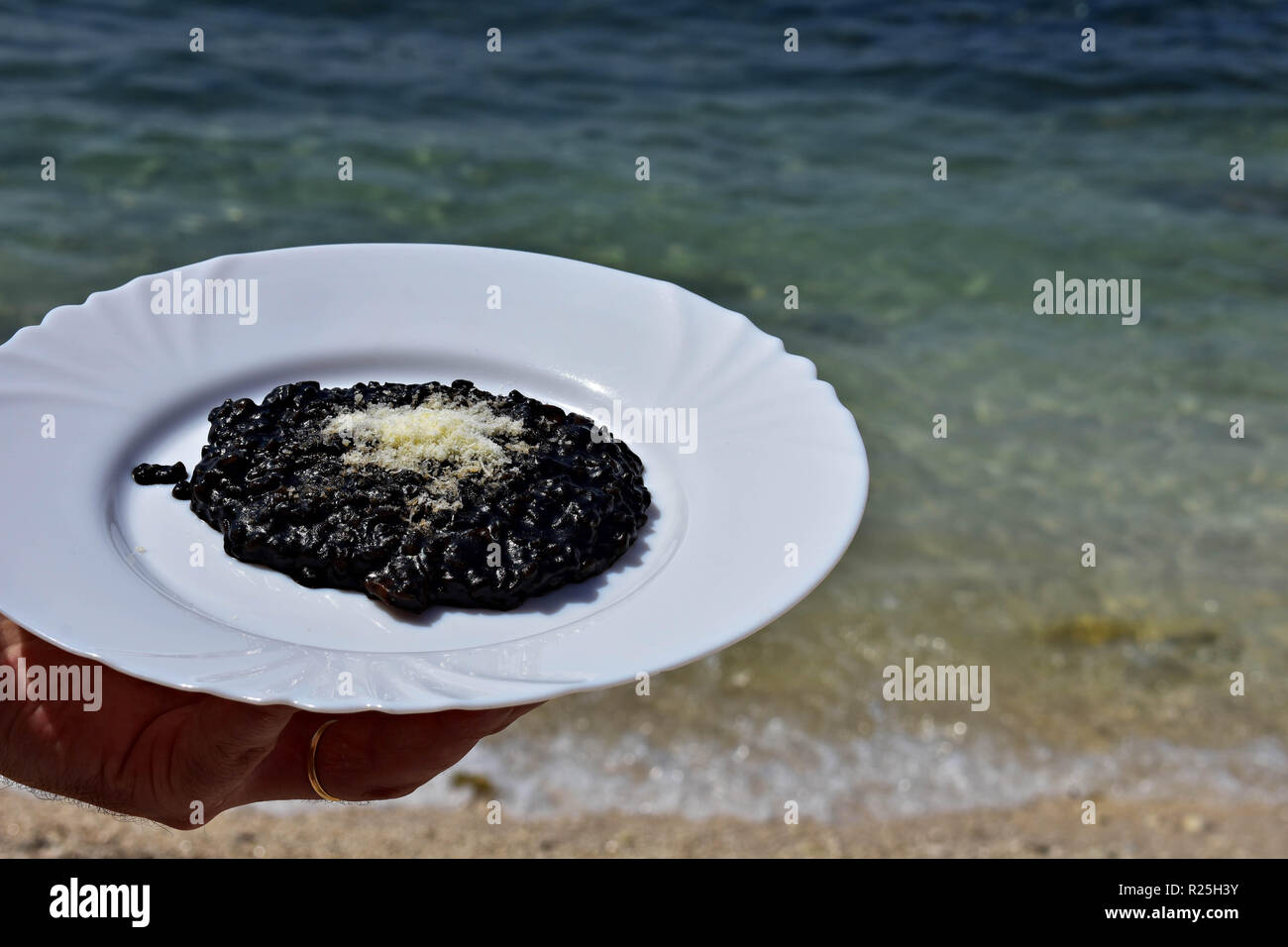 Nero deliziosi risotti serviti dal mare/ cameriere tenendo la piastra del risotto nero / cucina mediterranea Foto Stock