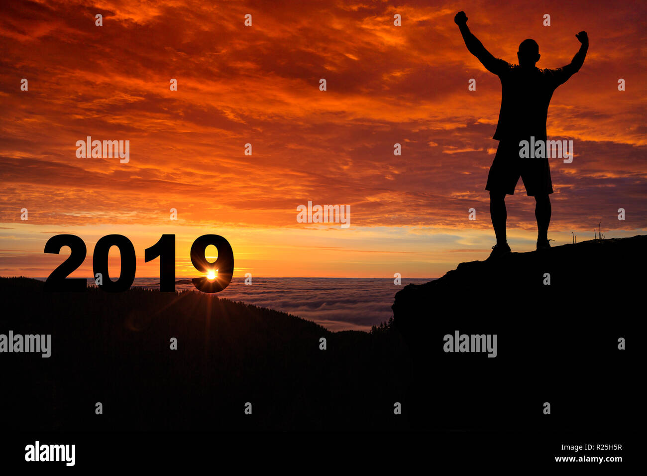 Silhouette uomo sulla cima della montagna a guardare il tramonto e 2019 anni mentre celebrava l. Foto Stock