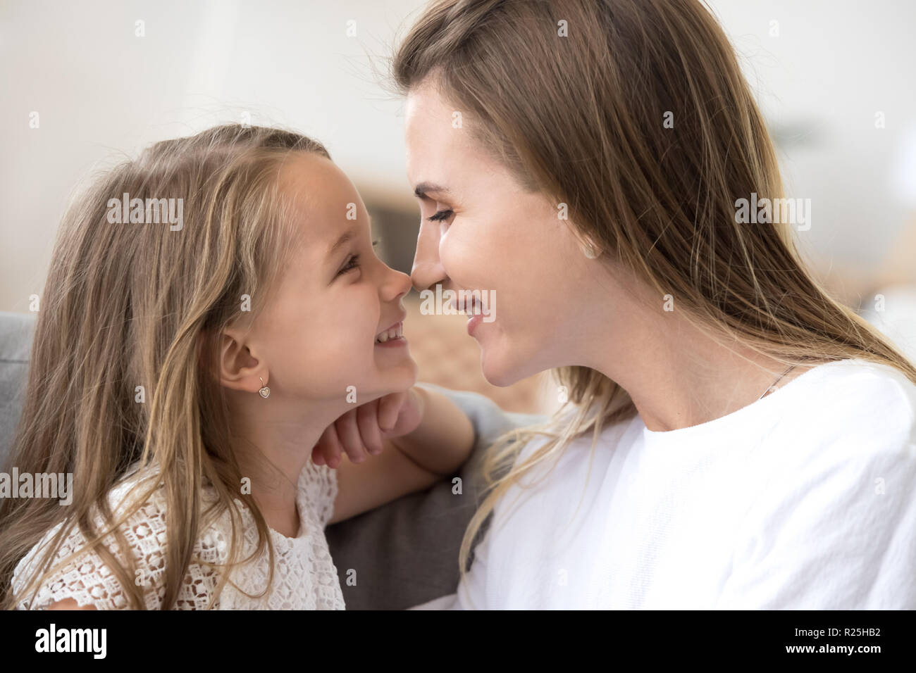 Sorridente carina ragazza di capretto e madre di toccare nasi esprimendo tende Foto Stock
