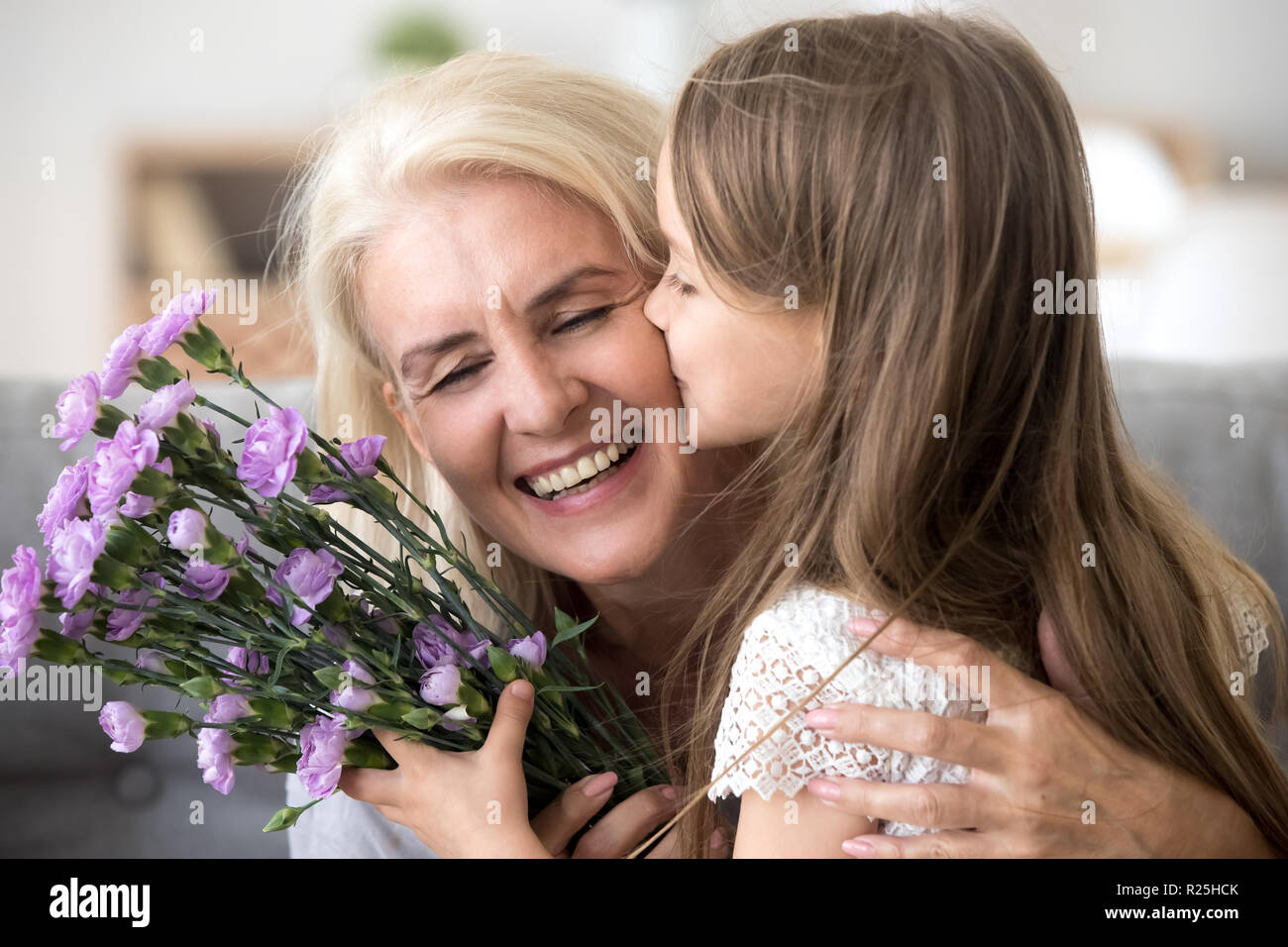 Piccolo nipote kissing dando bouquet di fiori congratulati Foto Stock