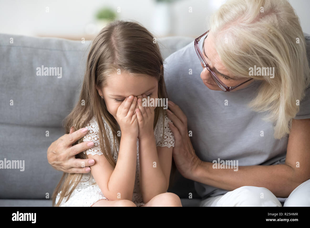 Amorevole comprensione nonna abbracciando poco ragazza che piange comfor Foto Stock