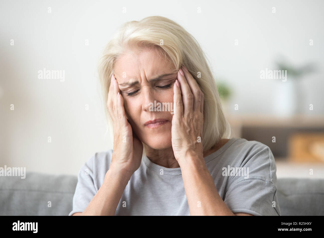 Sconvolto donna anziana toccando templi testa dolorosa sensazione forte egli Foto Stock