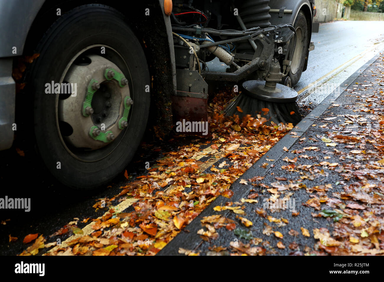 Un consiglio spazzatrice stradale mostrato di pulizia lascia lungo la strada a Chichester, West Sussex, Regno Unito. Foto Stock