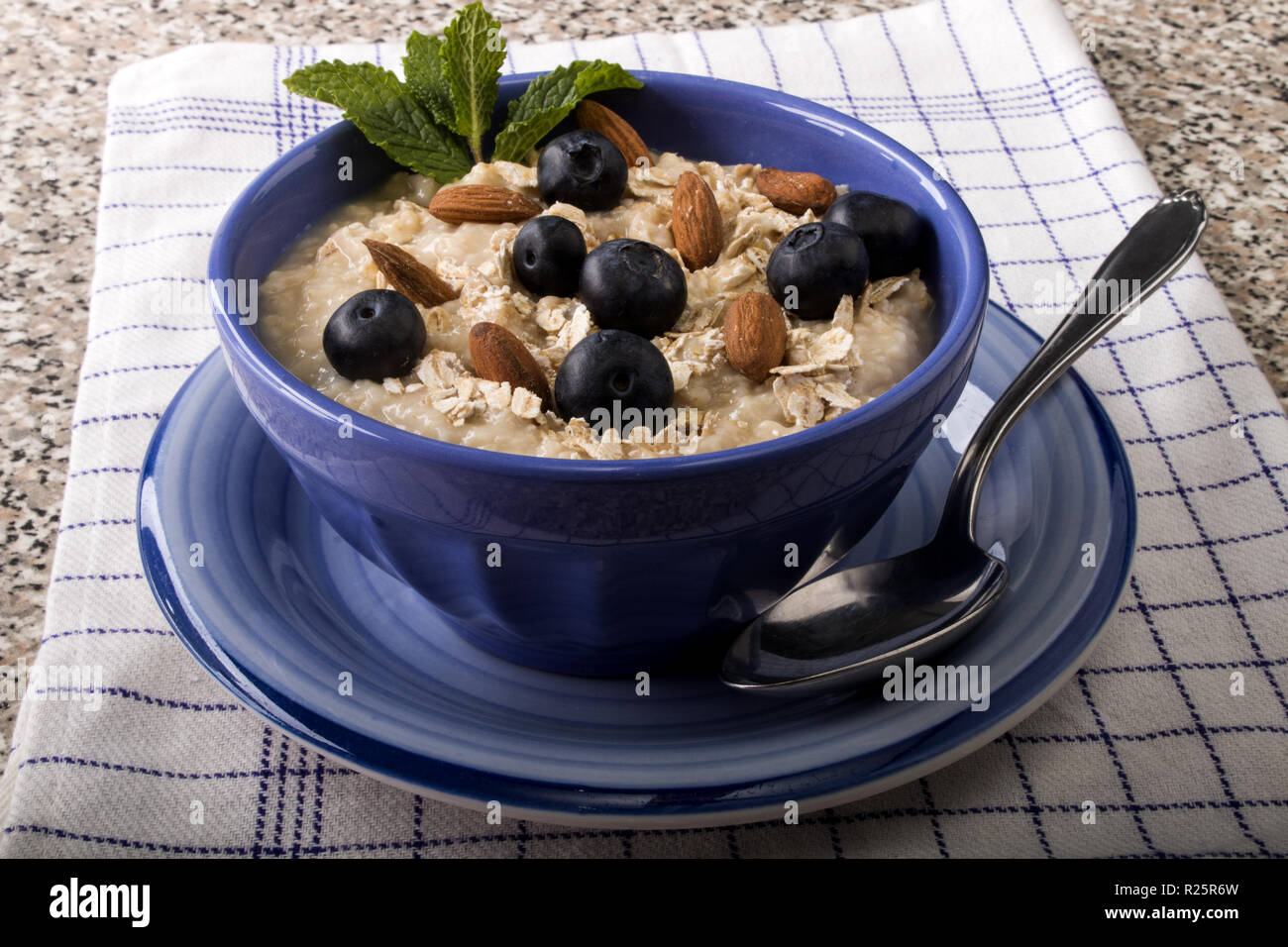 Il porridge realizzato con i tradizionali irlandesi, fiocchi d'avena i mirtilli, le mandorle in una ciotola blu Foto Stock