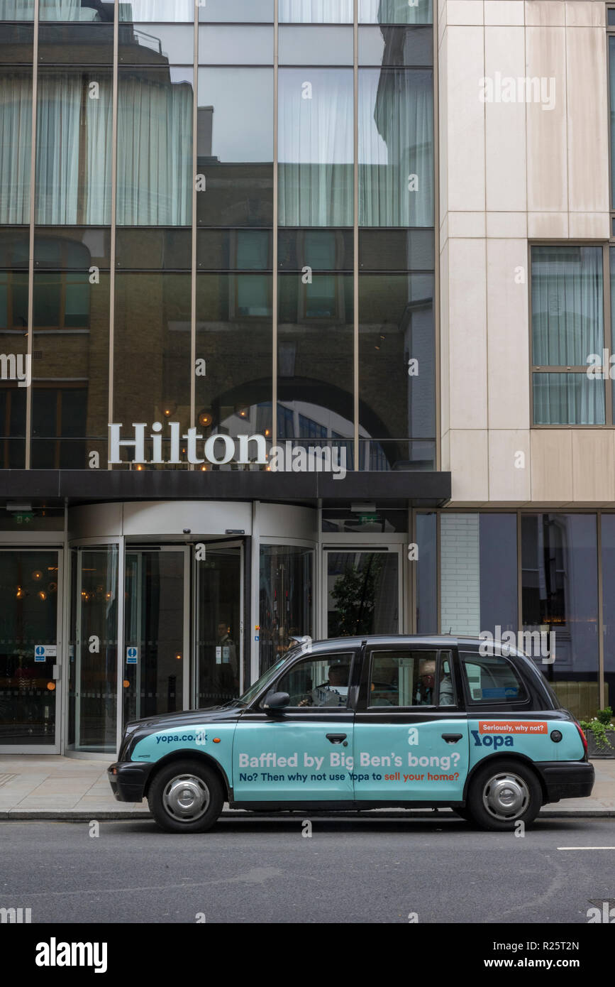 Un London Black Cab o taxi in attesa al di fuori dell'Hilton hotel nel centro di Londra. Foto Stock