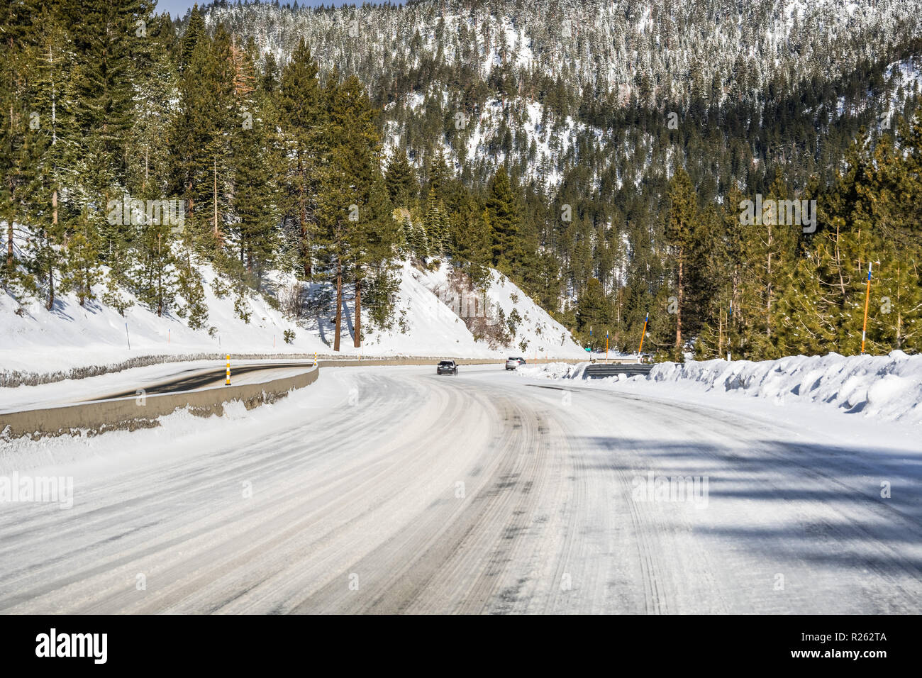 La guida su ghiaccio e neve coperto la strada attraverso le montagne di Sierra in una giornata di sole, Nevada Foto Stock