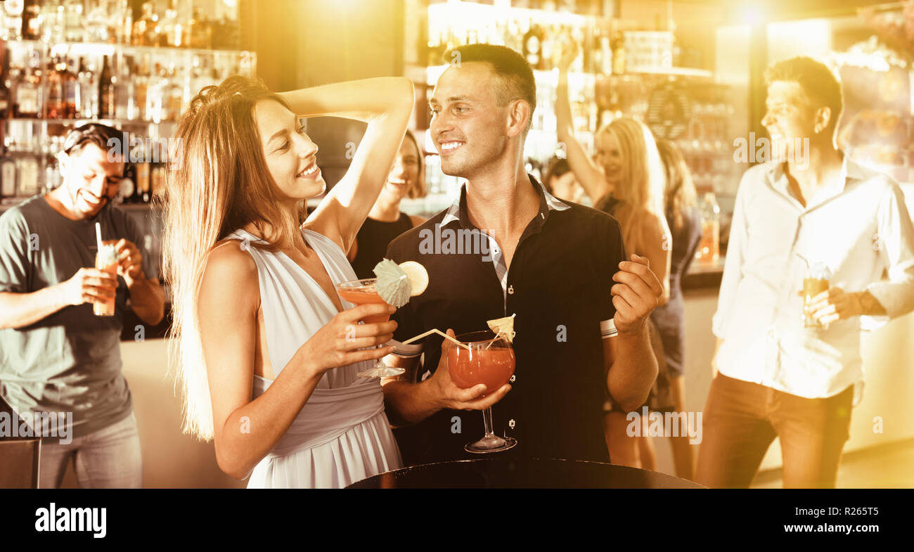 Felice allegro positivo uomo sorridente con la donna stanno bevendo un cocktail sulla corporate partito. Foto Stock