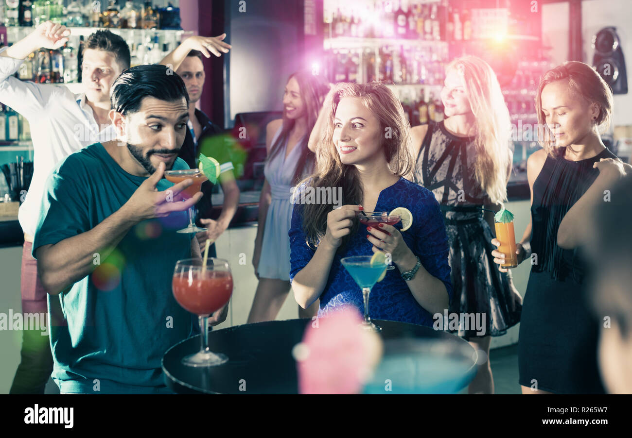 Gioiosa maschio con femmina sono a parlare e a bere un cocktail sulla parte in club Foto Stock