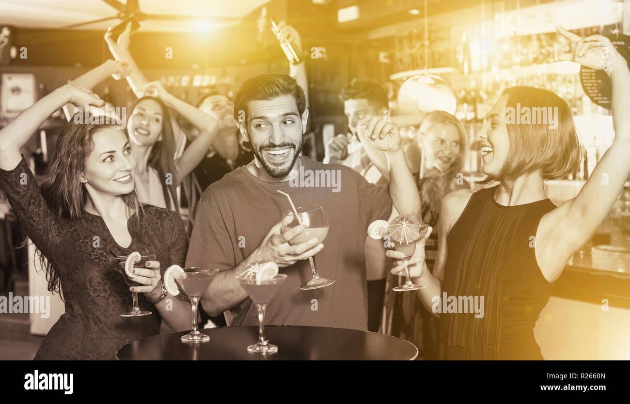Uomo con due donne stanno bevendo un cocktail sulla parte aziendale Foto Stock