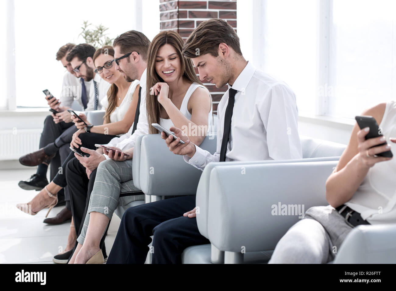 Un gruppo di dipendenti che utilizzano la loro gadget seduta nel corridoio di office Foto Stock