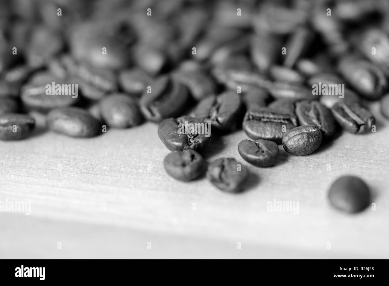 Chicchi di caffè tostati su uno sfondo di legno. In bianco e nero Foto Stock