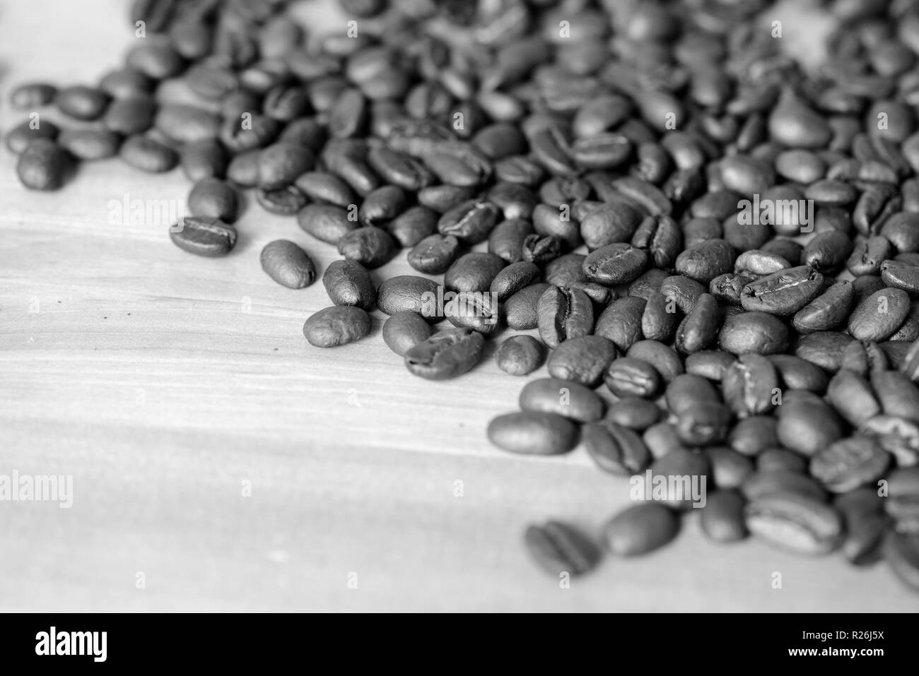 Chicchi di caffè tostati su uno sfondo di legno. In bianco e nero Foto Stock
