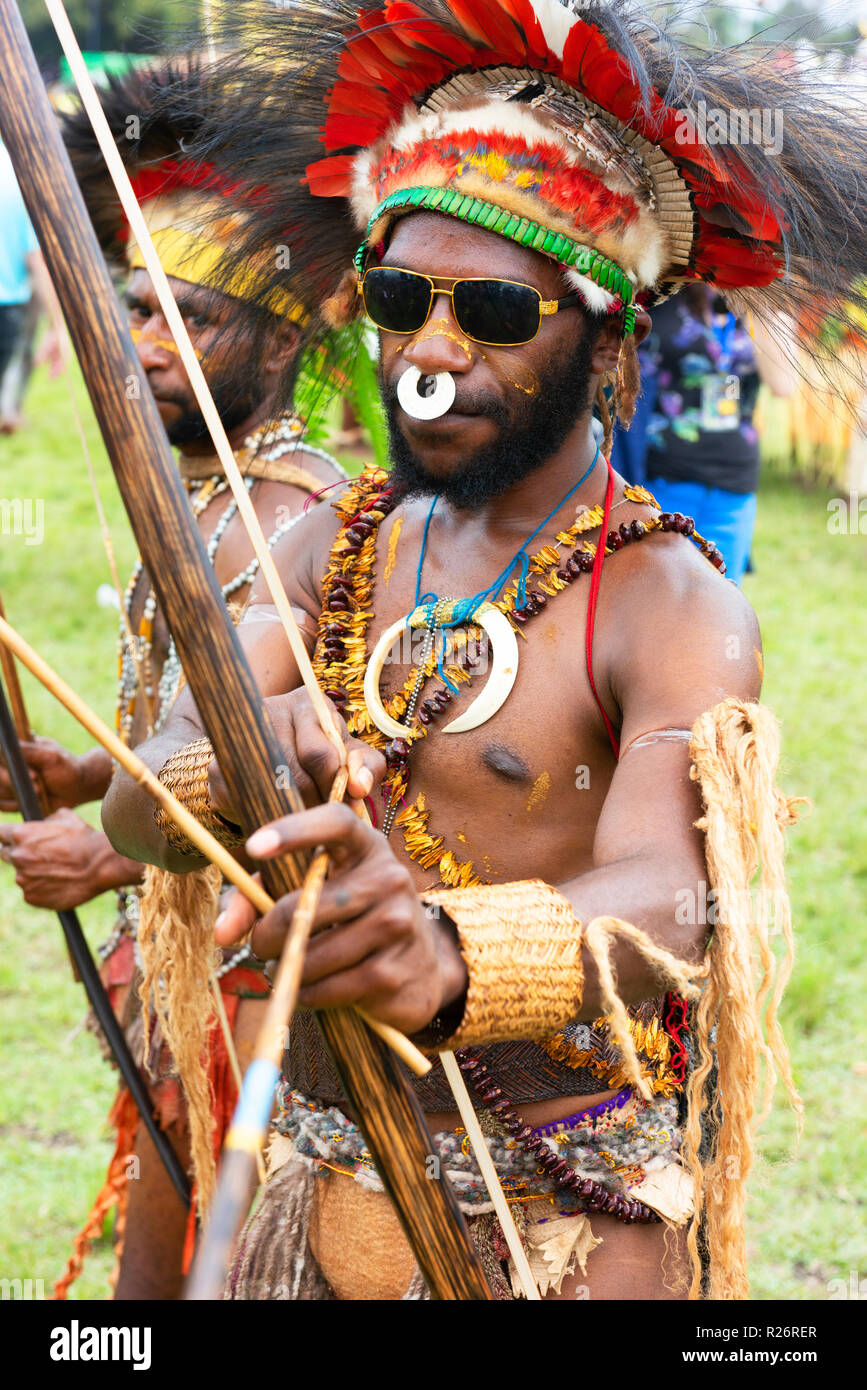 Uomo in costumi tradizionali e moderni occhiali da sole esegue presso il Festival di Goroka. Foto Stock