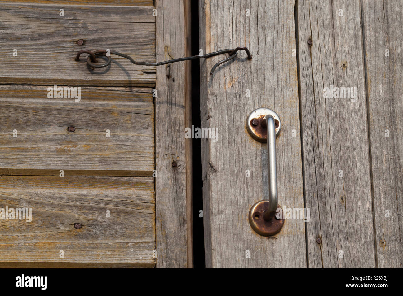 Vecchia maniglia in metallo e gancio, che ha chiuso la porta di legno del granaio, primo piano Foto Stock