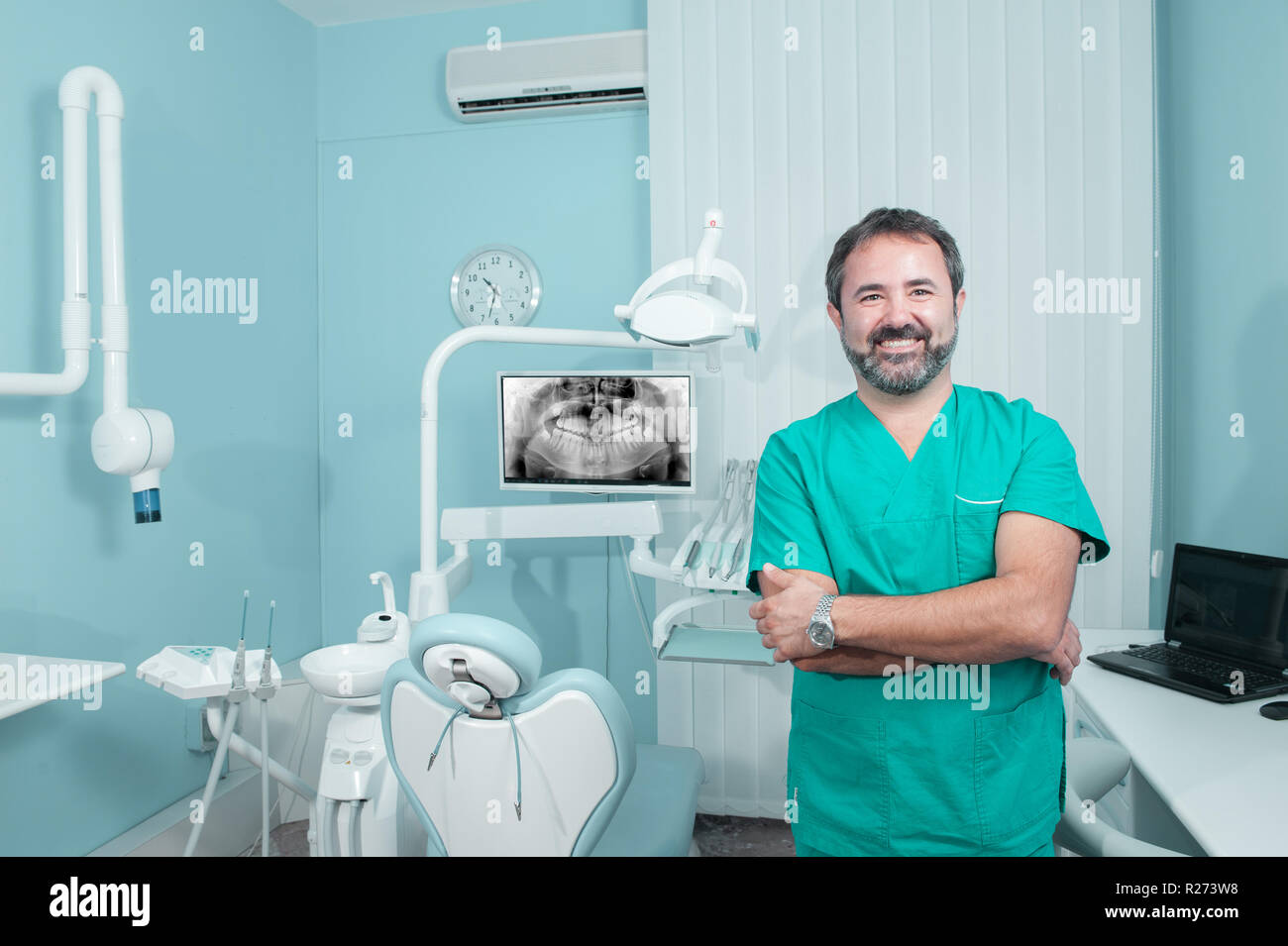 Sorridente maschio caucasico medico guardando la fotocamera in studio dentista, panoramica x-ray sullo schermo, una persona, modello rilasciato Foto Stock