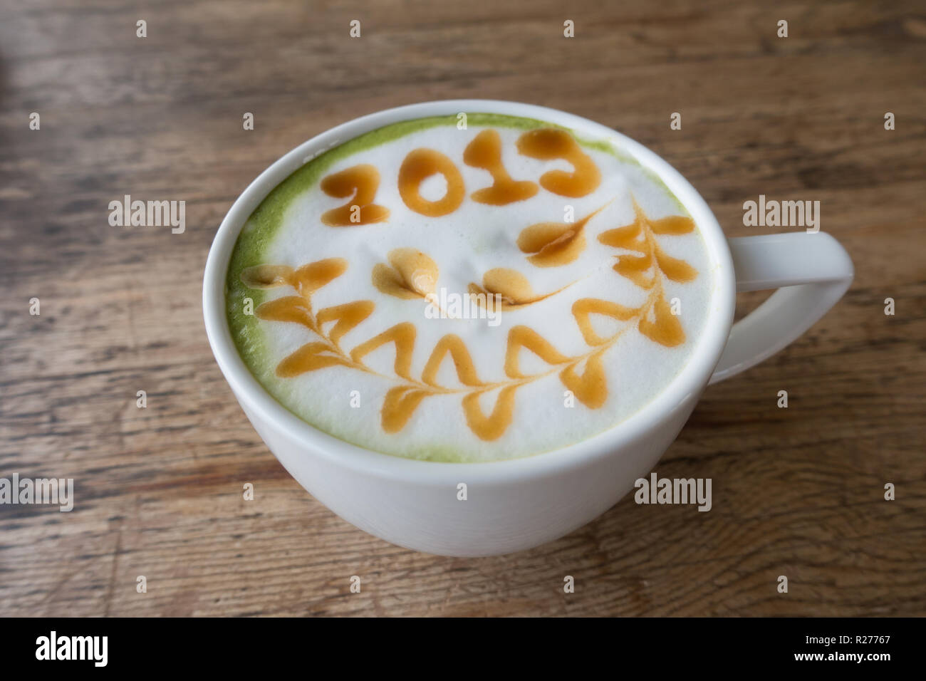 Il tè verde con la schiuma di latte art 2019 sul tavolo di legno Foto Stock