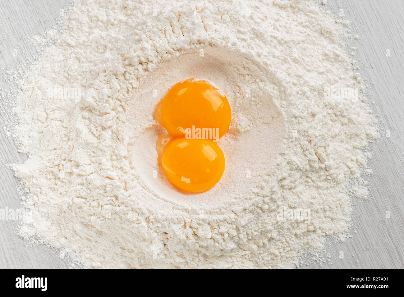 Tuorli di uova sulla farina bianca per pasta, vista dall'alto sulla tabella. Foto Stock