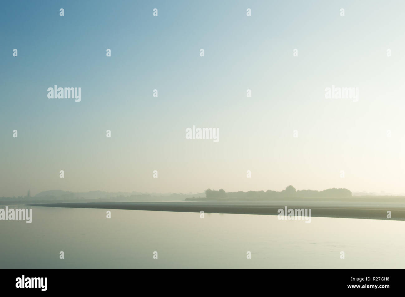 Un minimo di composizione del paesaggio di un fiume in una nebbiosa mattina presto. Foto Stock