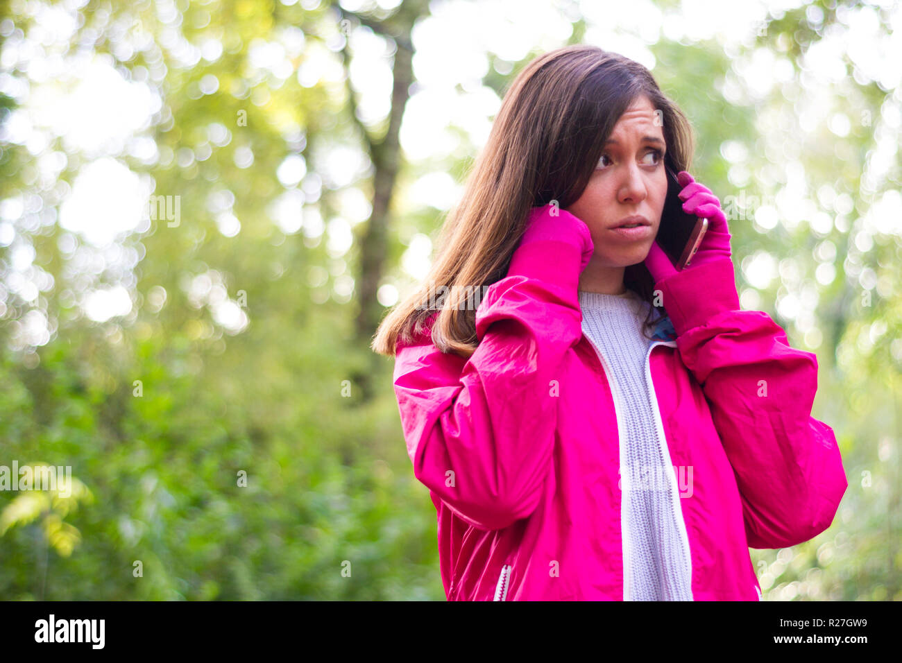 Giovani lonely brunette girl al riparo nella foresta chiamando dal telefono cellulare preoccupato perché lei è stato perso nel selvaggio Foto Stock