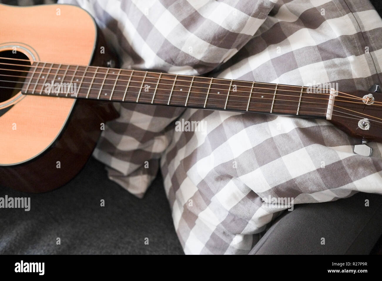 Chitarra acustica giacente su un divano Foto Stock