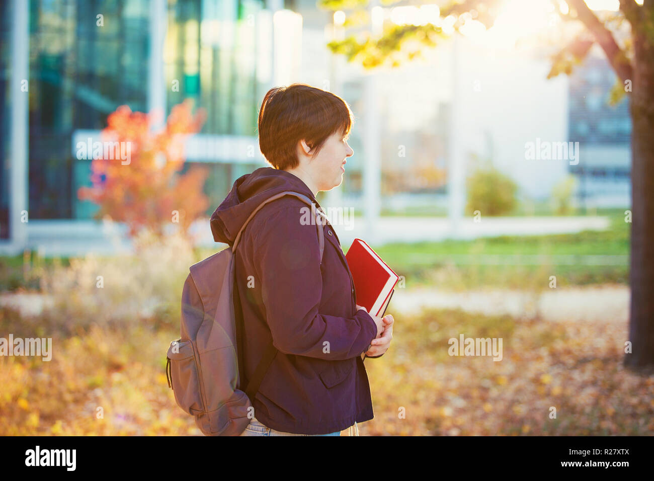 Giovane donna passeggiate all'aperto, vista laterale studente ritratto contenere libri e zaino, il concetto di istruzione. Foto Stock