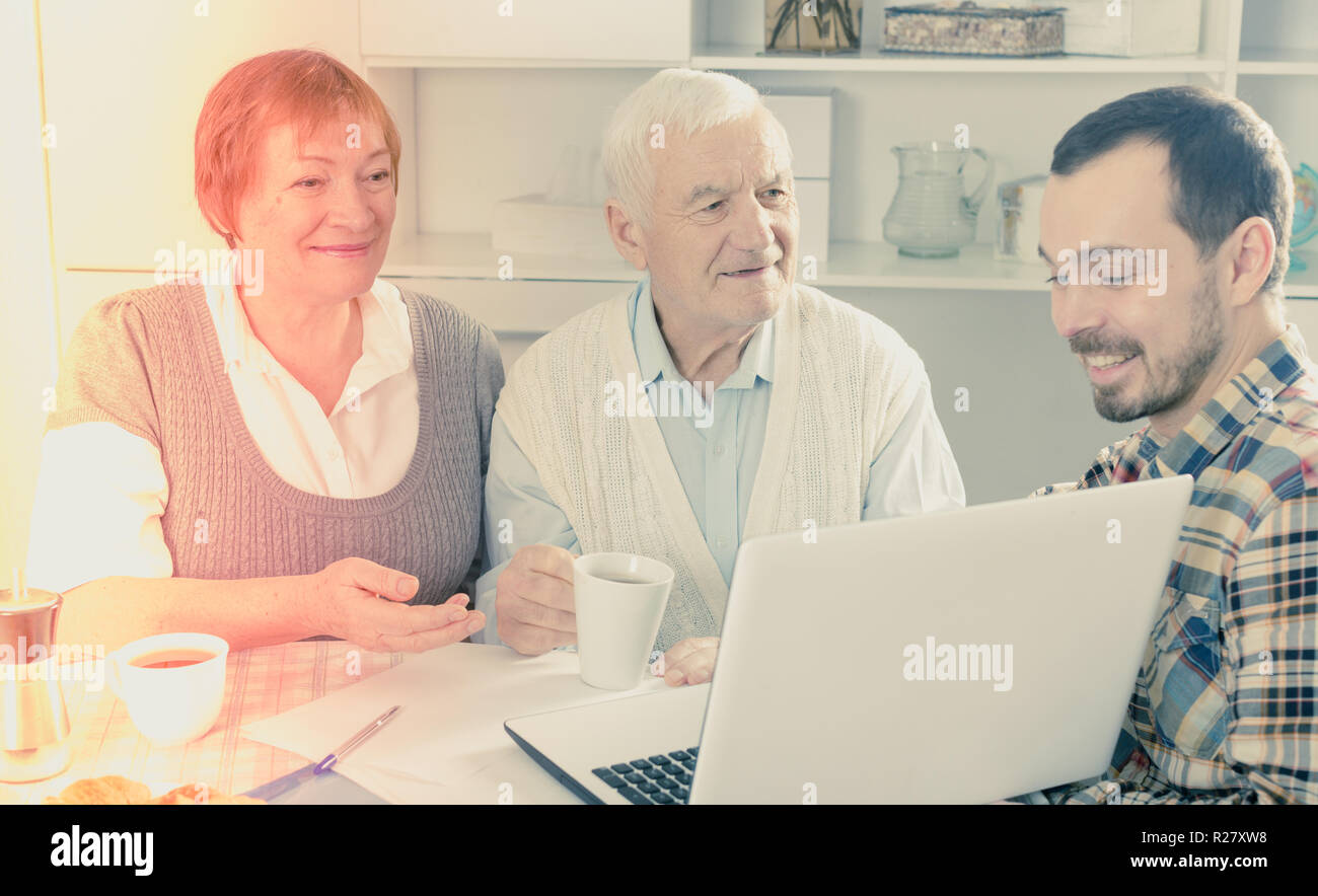 Famiglia sorridente guardando interessanti notizie e video su Internet su notebook a casa Foto Stock