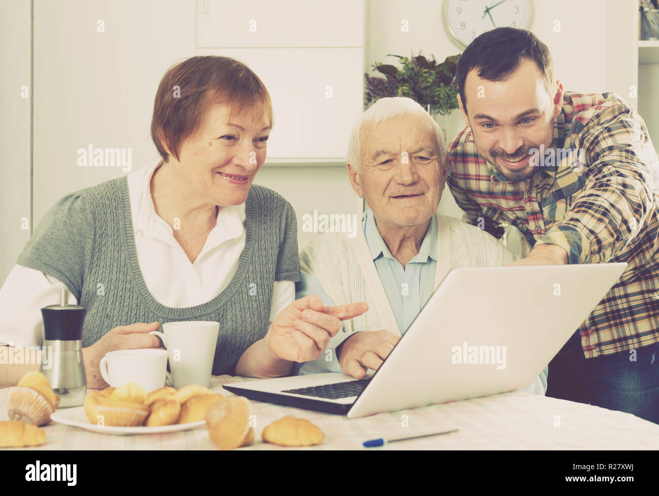 Famiglia sorridente guardando interessanti notizie e video su Internet su notebook a casa Foto Stock
