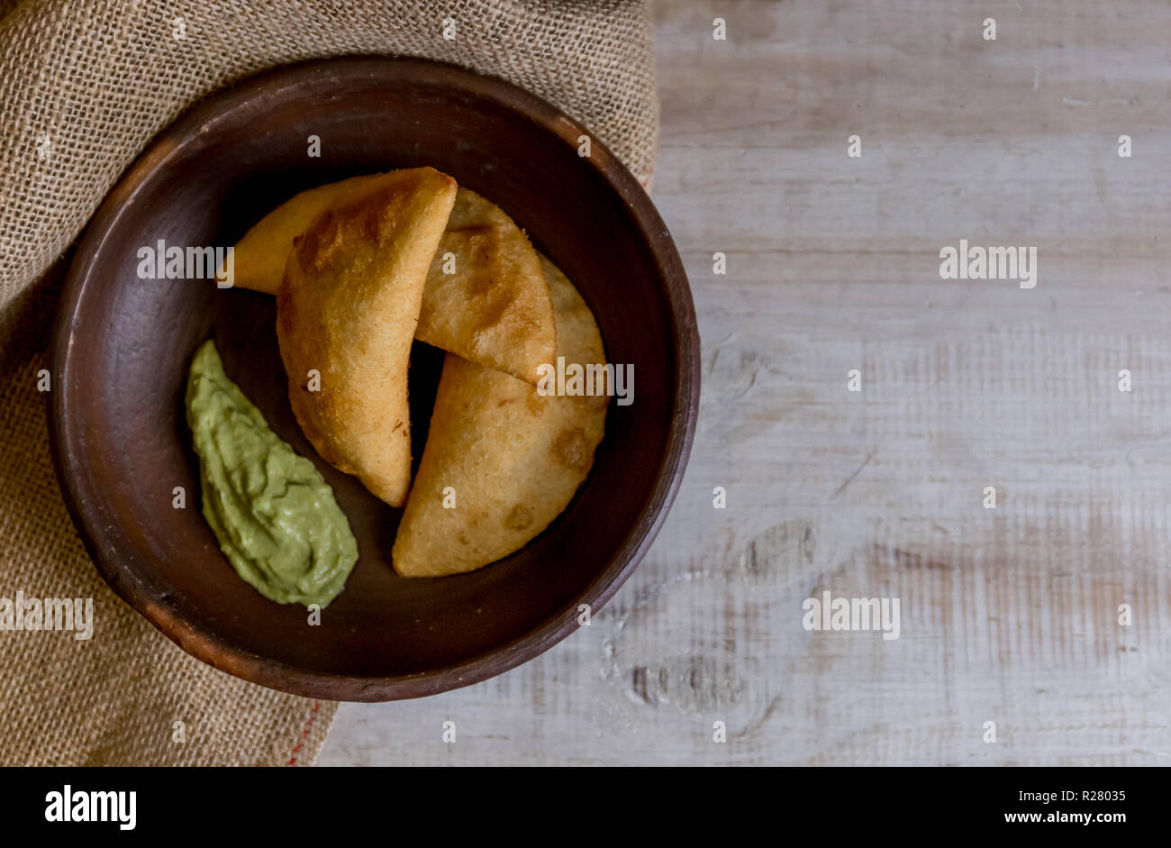 Venezuela e Colombia cibo. Venezuelano di mais tipici empanadas con carne nella terrina di argilla con salsa di avocado. Foto Stock