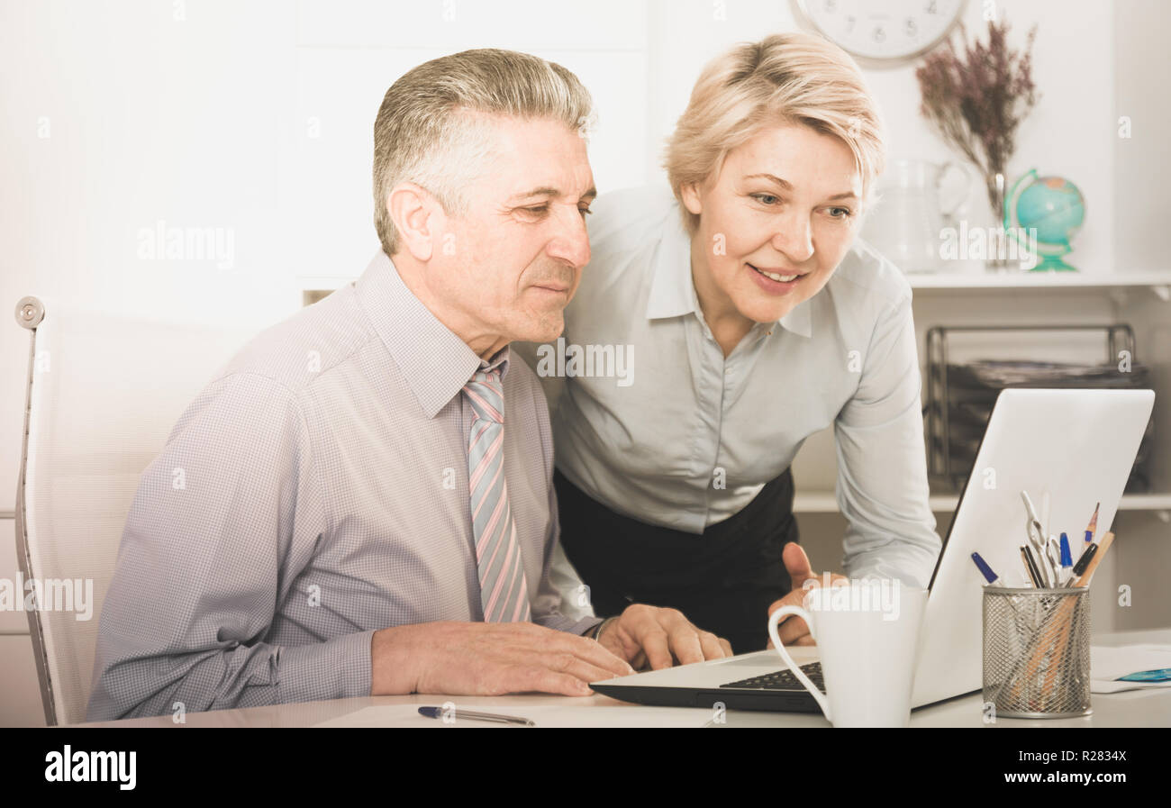 I colleghi sorridente cercare informazioni interessanti su Internet sul computer portatile alla reception a ofice Foto Stock