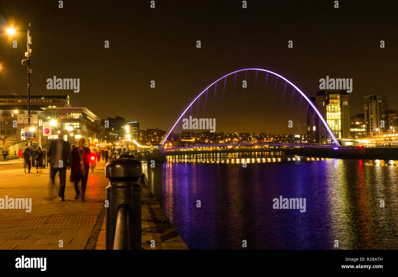 Newcastle Upon Tyne, England, Regno Unito, 17 novembre 2018. Vista dalla banchina del porto con la gente a piedi lungo il Fiume Tyne del pedone Gateshead Millennium Bridge e la Rank Hovis ha Baltic mulino di farina ora Baltic Centre for Contemporary Art pit fino a notte con riflessi nell'acqua Foto Stock