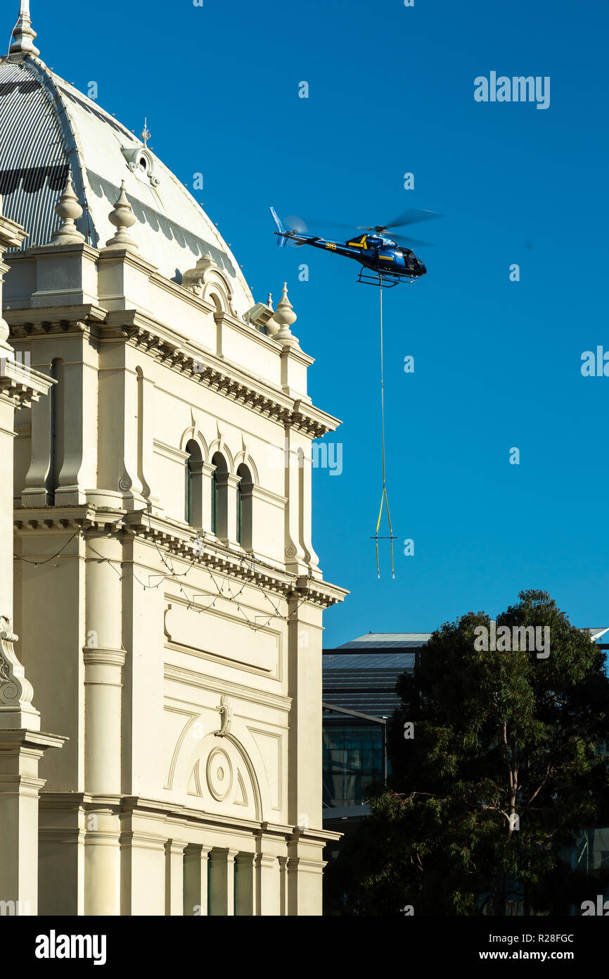 Melbourne, Australia. Xviii Nov, 2018. Carlton residenti si risvegliano in una vista spettacolare di questo fine settimana come un basso-volo in elicottero a opere attentamente le casse di manovra dei pannelli solari dalla motivazione dei giardini Carlton precinct al tetto dell'iconico Melbourne Museum building. La collaborazione con la tecnologia globale società Siemens Ltd, musei Victoria è nel processo di installazione di oltre 2.700 pannelli solari, creando una 1083kW solar array - il più grande solar array nella metropolitana di Melbourne. Credito: Dave Hewison sport/Alamy Live News Foto Stock