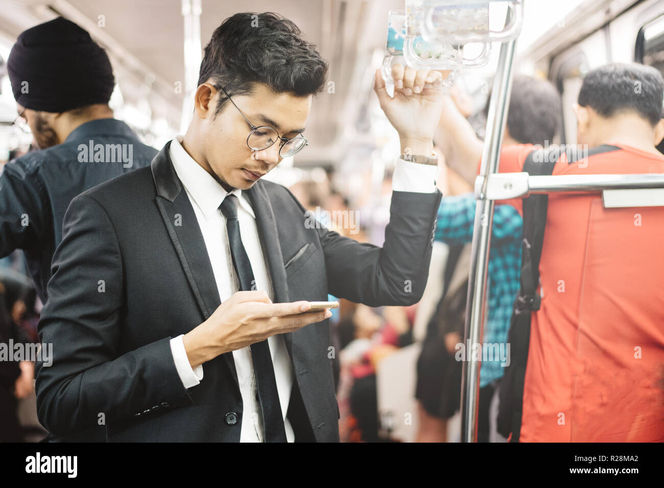 Giovane e bello imprenditore asiatico tramite smartphone in un treno dei pendolari. concetto di gente di affari e la tecnologia wireless Foto Stock